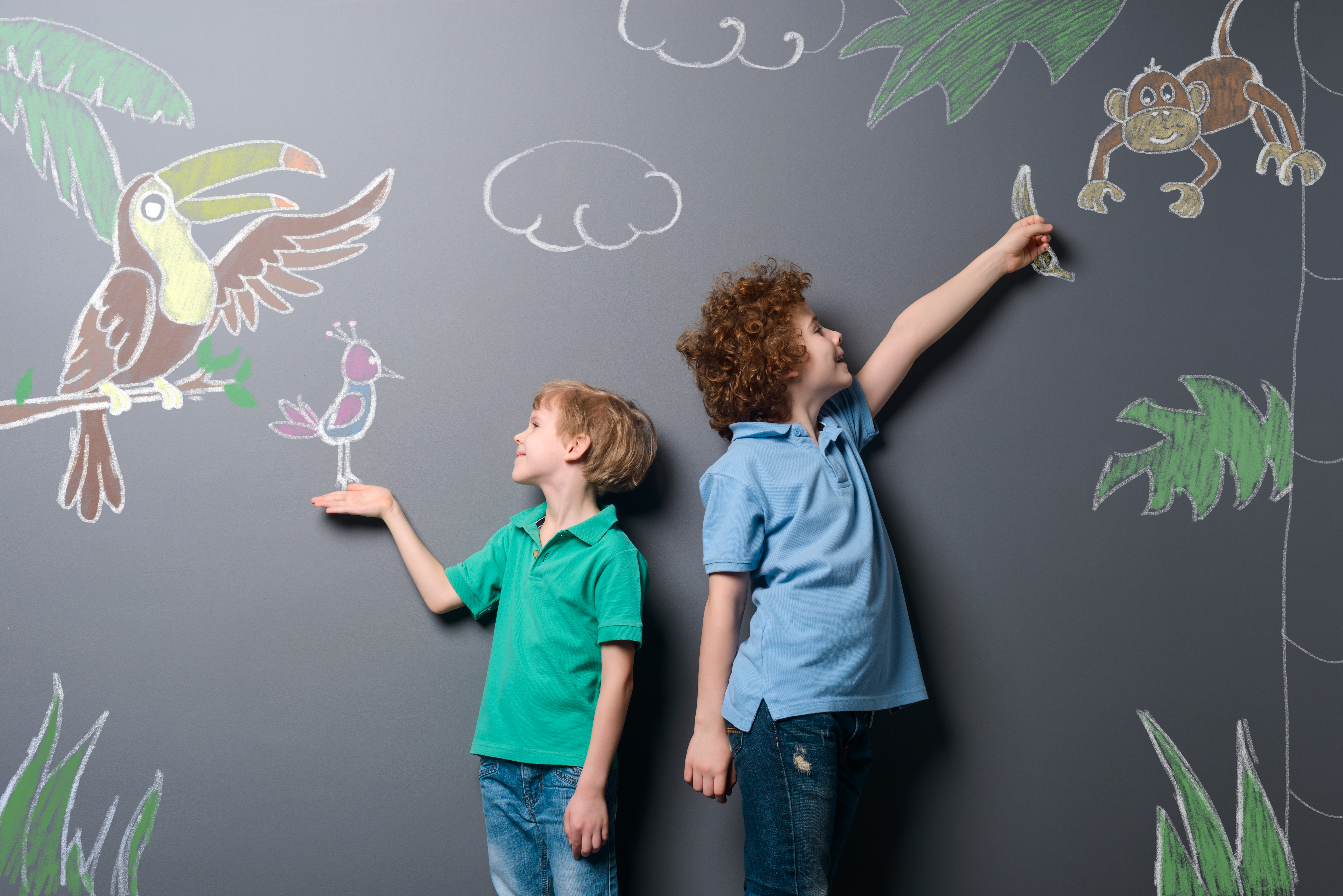 Boys walking through tropic forest. Two brothers feeding beautiful exotic birds and monkey drawn with chalk on a gray wall.