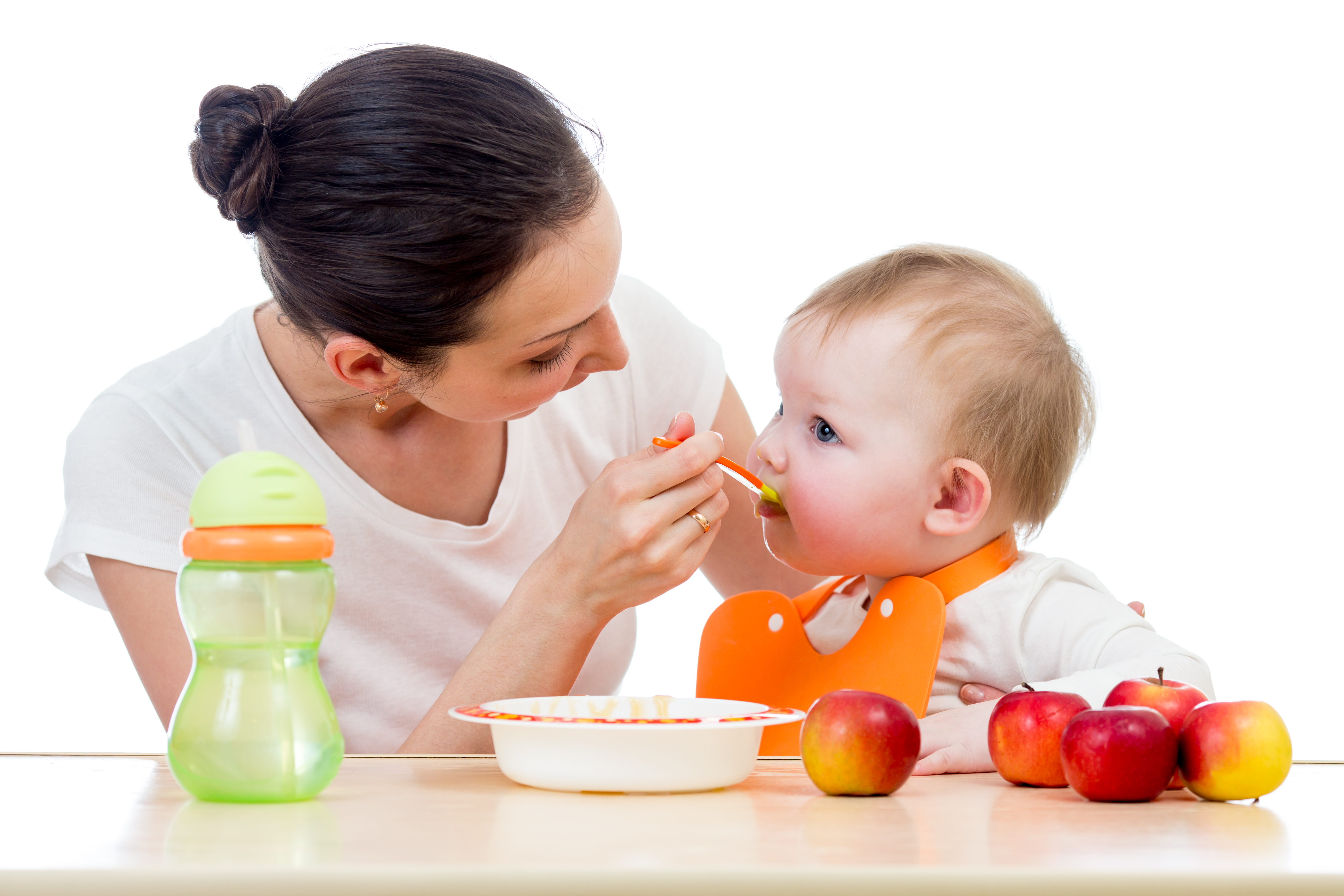 young mother spoon feeding her baby girl